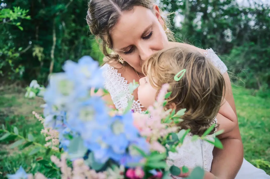 Une femme en robe de mariée embrassant tendrement son enfant